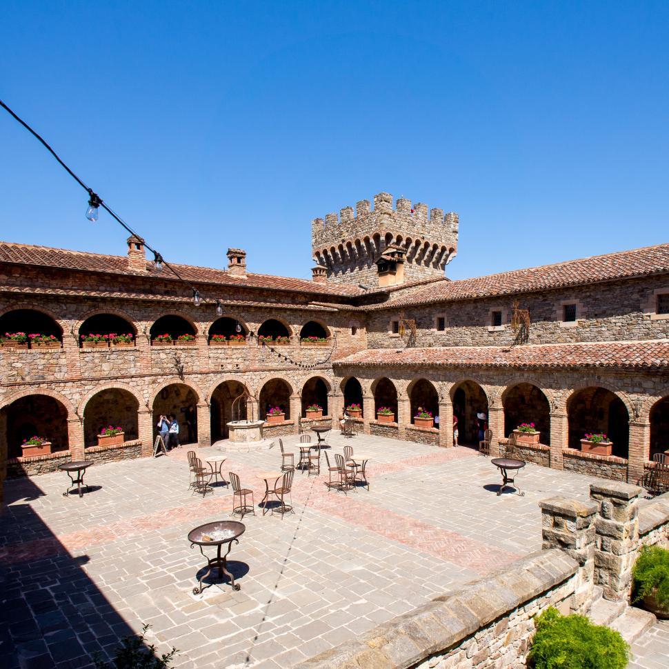 Free Image of Historic castle courtyard with tables under blue sky. 