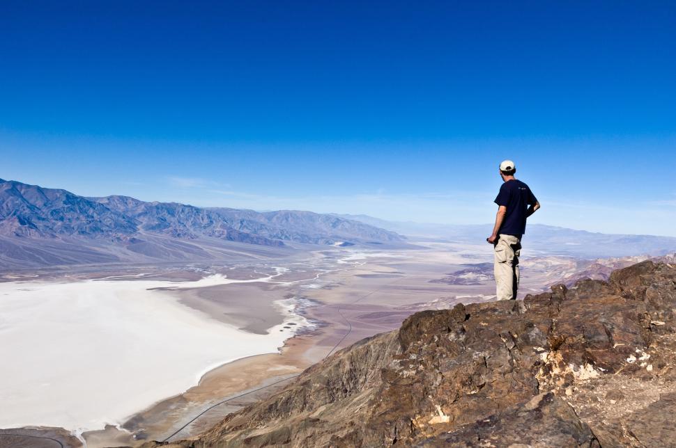 Free Image of Person standing on mountain peak overlooking vast desert. 
