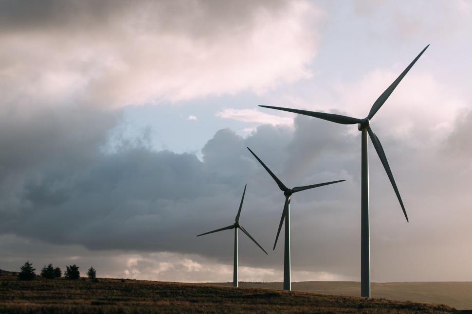 Free Image of Three wind turbines standing on a grassy landscape 