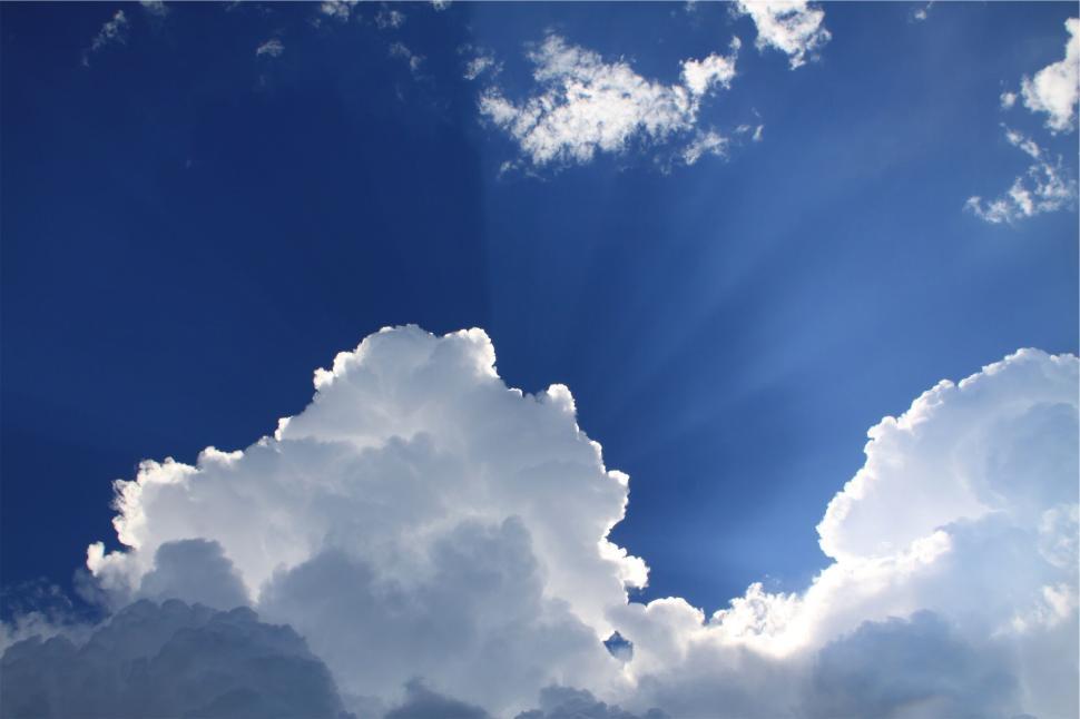 Free Image of Radiant sunlight pierces through fluffy white clouds 