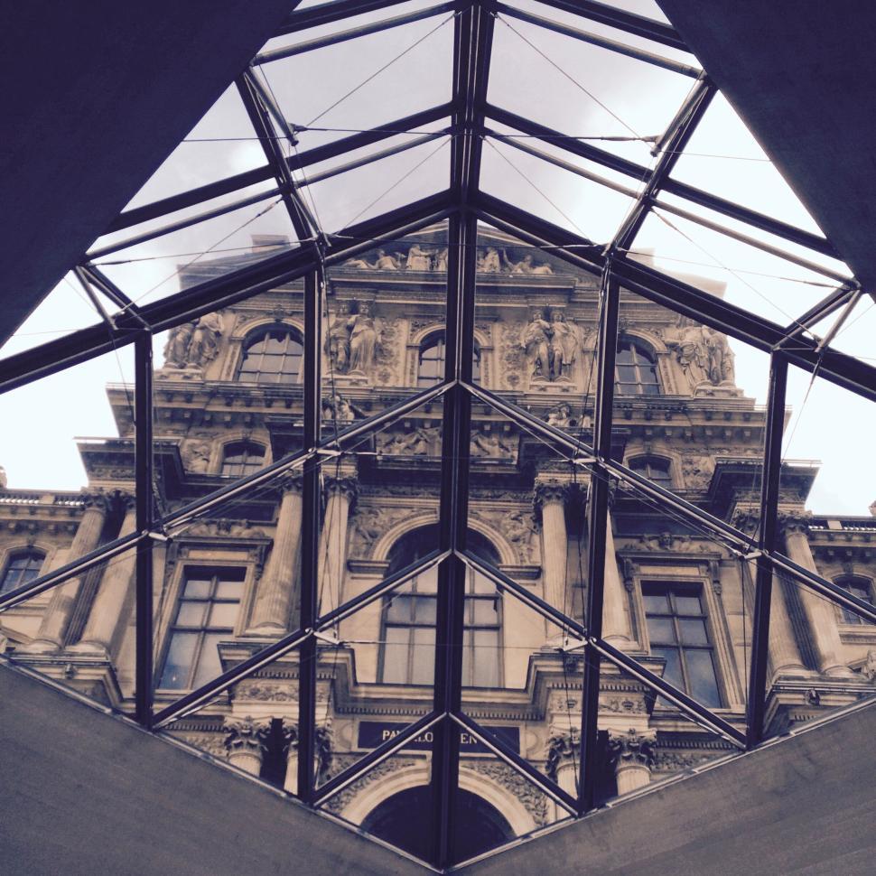 Free Image of Louvre Pyramid reflecting historic architecture under. 