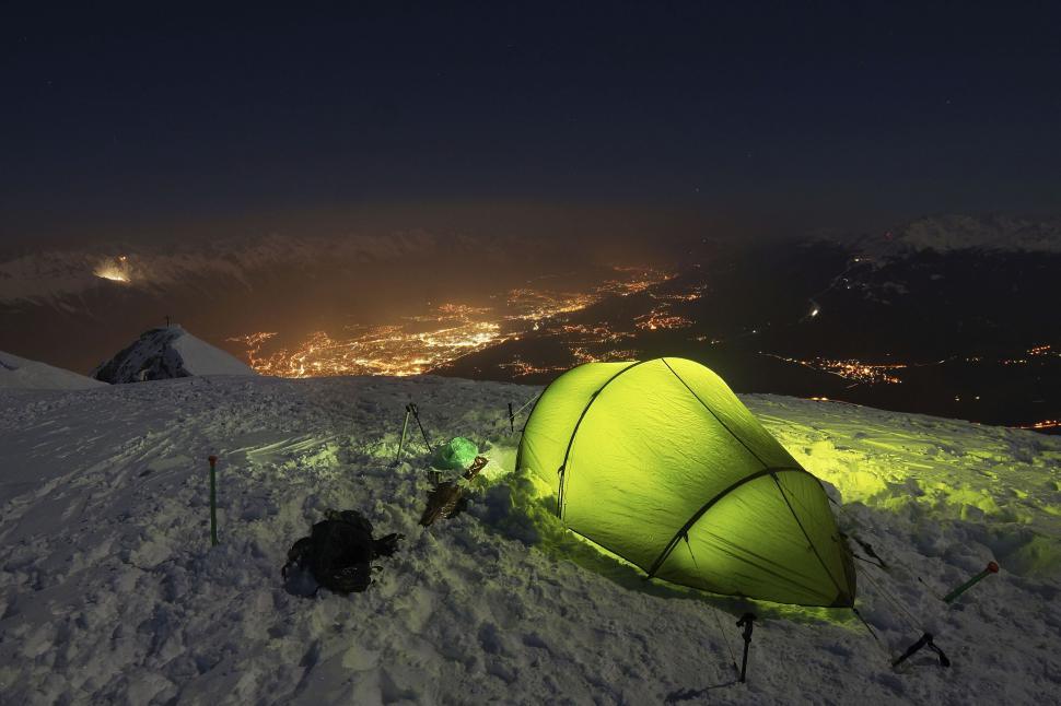 Free Image of Camping in snow at night with city lights in the distance. 