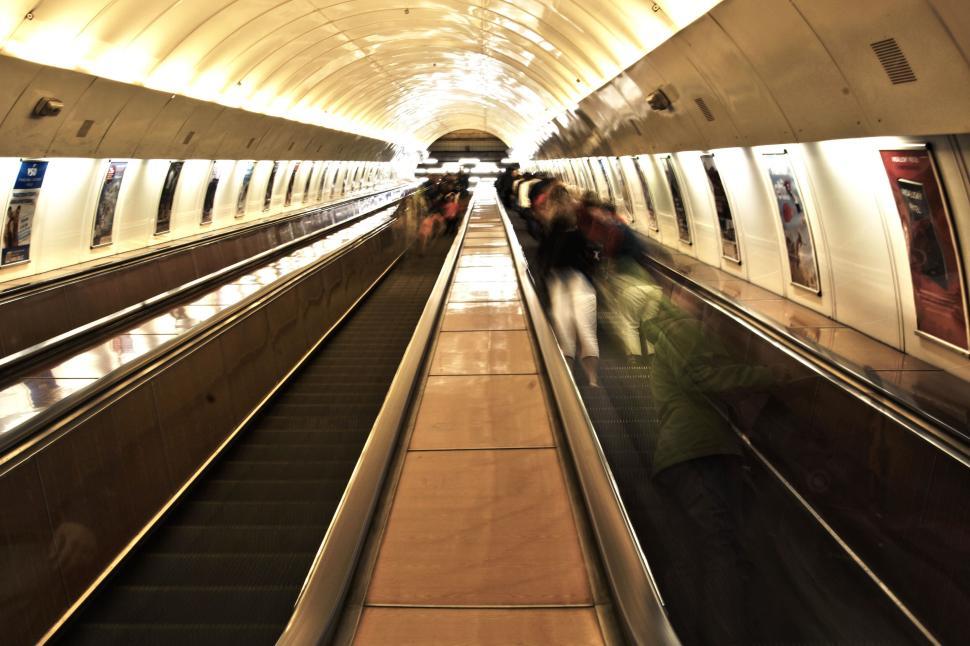 Free Image of Underground tunnel with escalators and people moving fast. 