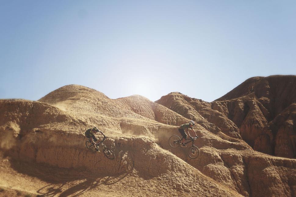 Free Image of Cyclists riding on a desert trail with rugged terrain. 