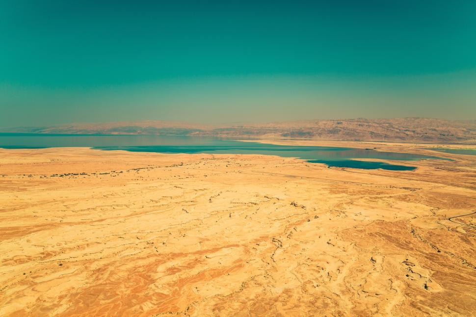 Free Image of Vast desert landscape with a distant body of water view 