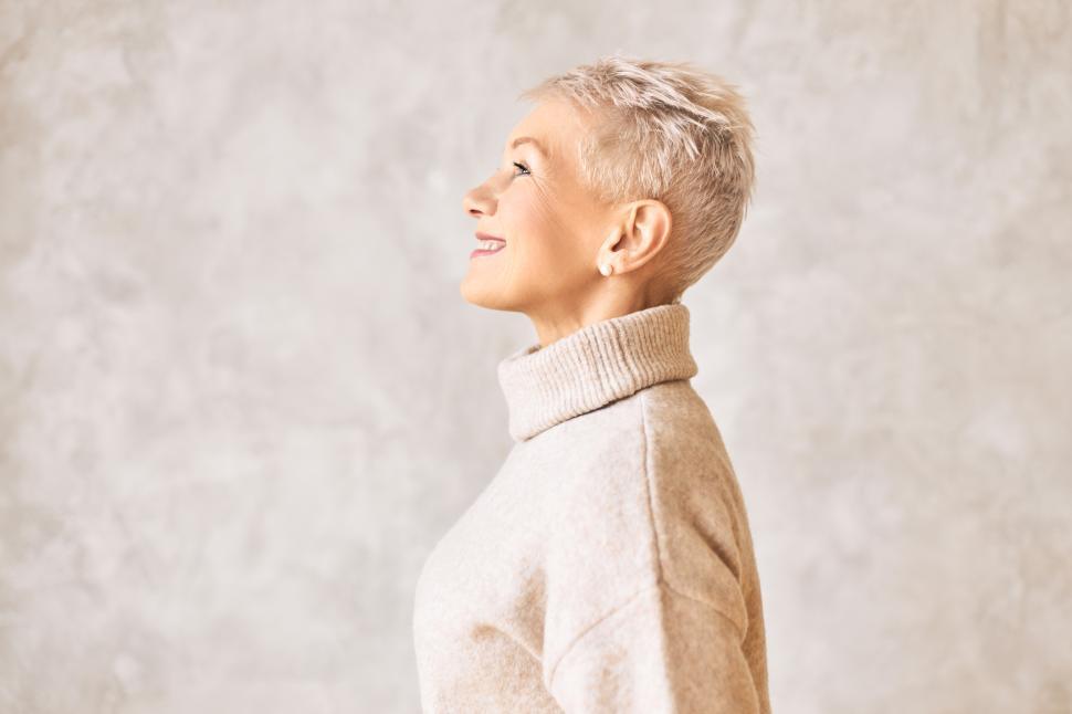 Free Image of Mature age, style and fashion concept. Side view of attractive fashionable European female pensioner posing isolated at marbled blank wall smiling, wearing stylish warm turtle neck sweater 