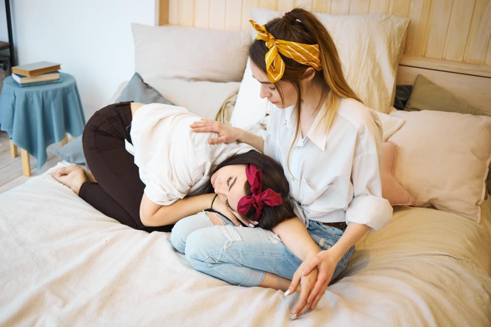 Free Image of Love, support and friendship concept. Portrait of desperate upset young woman feeling depressed because of break up with boyfriend, crying on lap of female friend who is consoling her in bedroom 