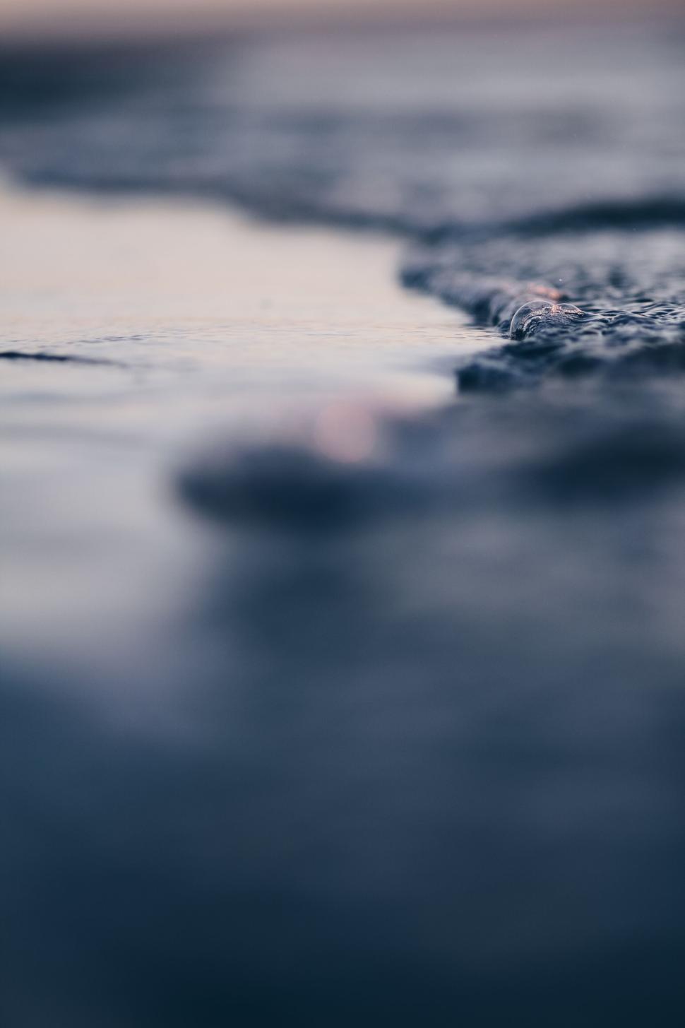 Free Image of Blurred shoreline with soft, shallow waves approaching 