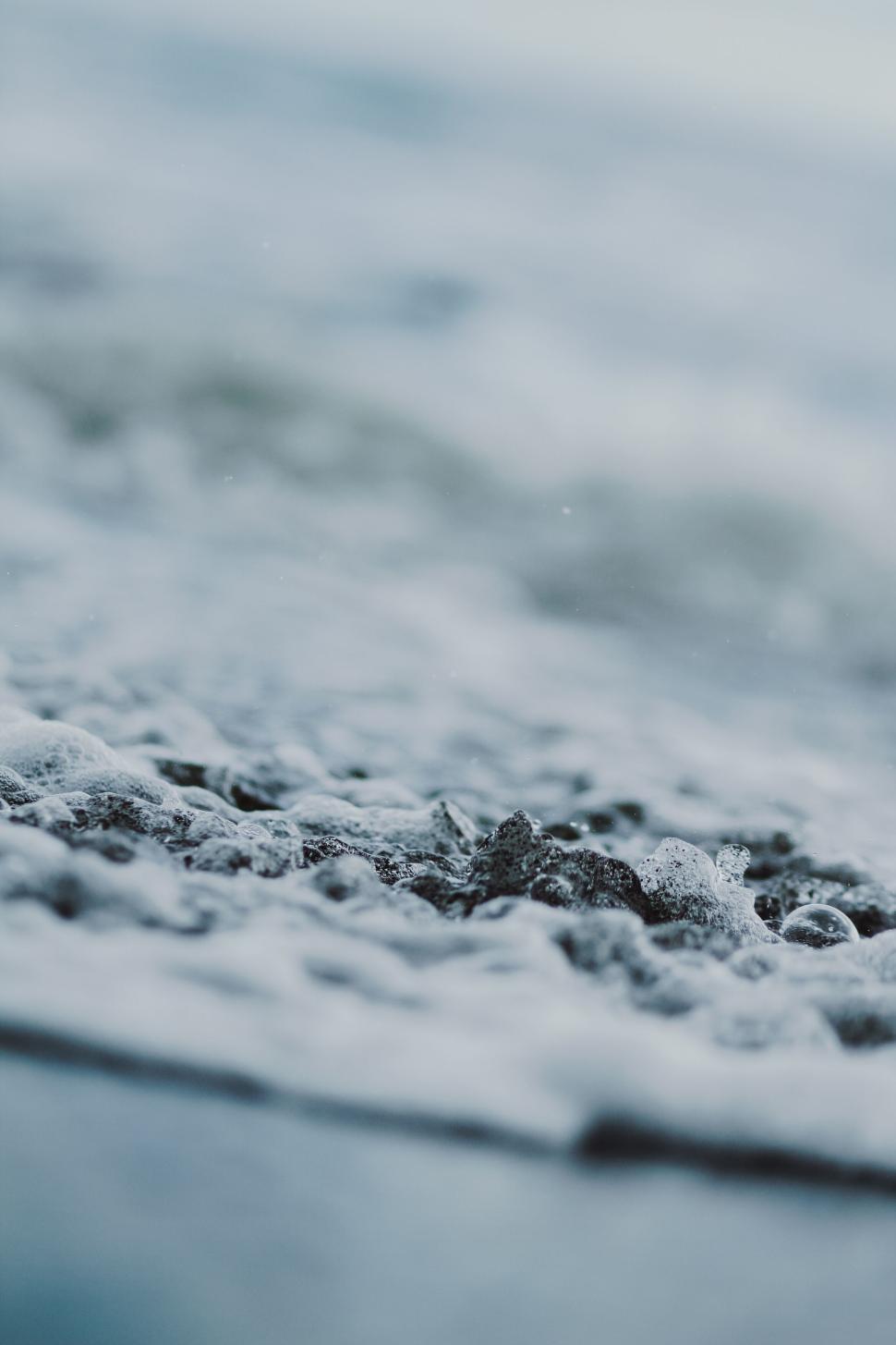 Free Image of Close-up of frothy ocean water on rocky shore 
