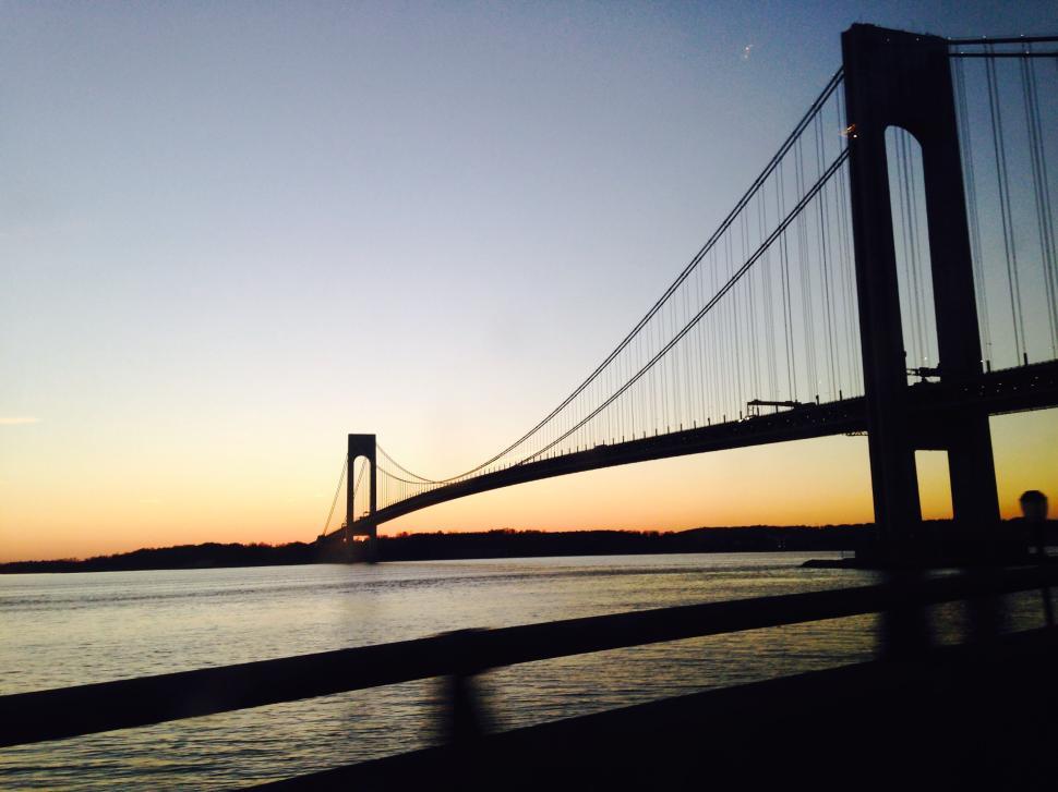 Free Image of Sunset view of a suspension bridge over calm water. 