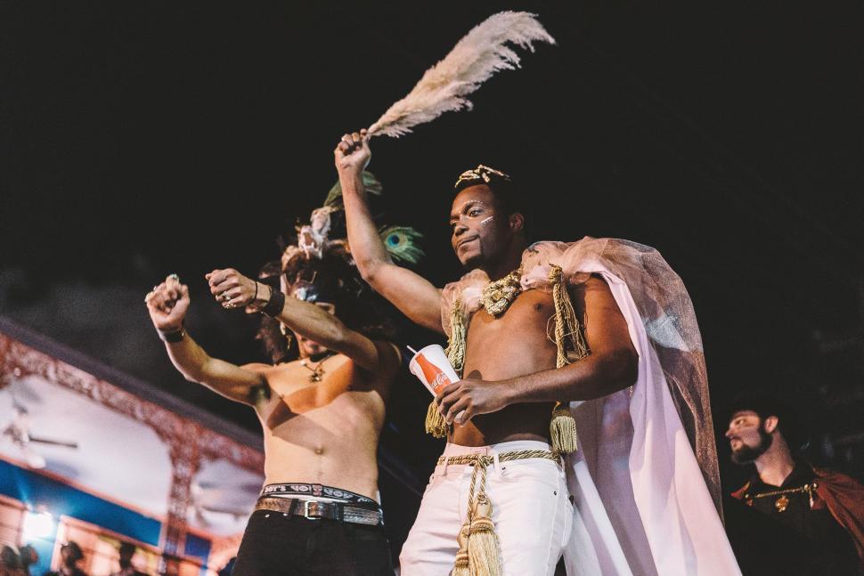 Free Image of Two men dancing in themed costumes at a vibrant event 