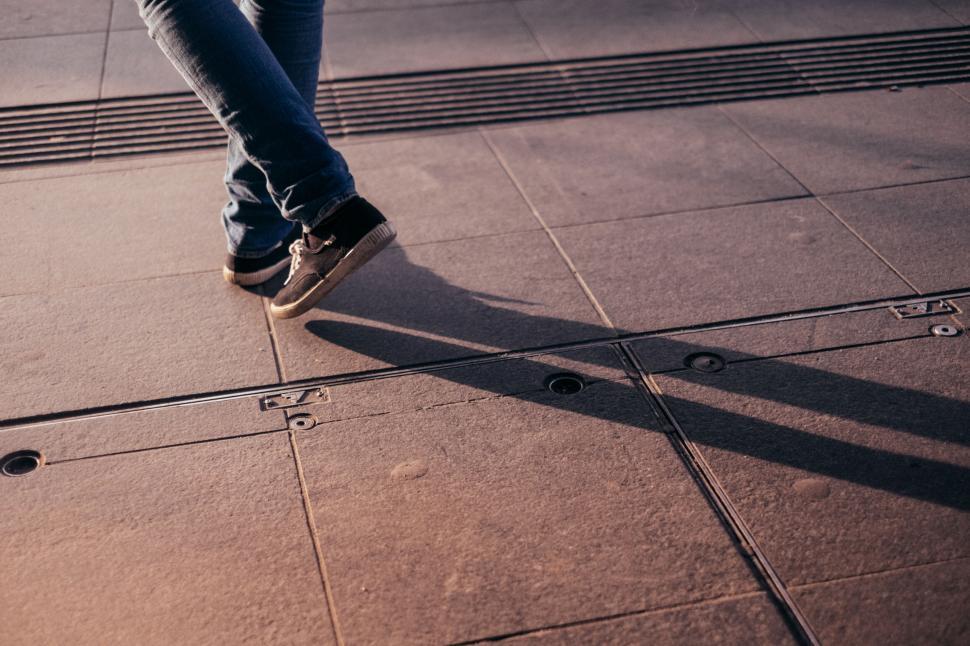 Free Image of Casual jeans and sneakers walking on urban pavement surface 