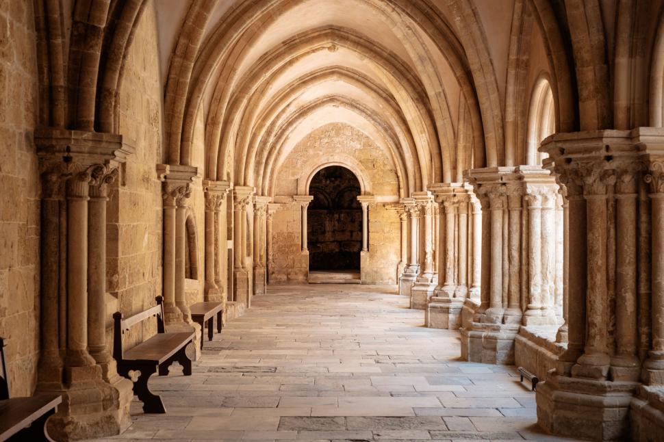 Free Image of Ancient stone cloister corridor with arched columns and shadows. 