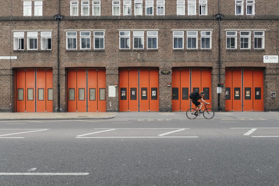 Free Image of Red fire station doors and cyclist on urban street 