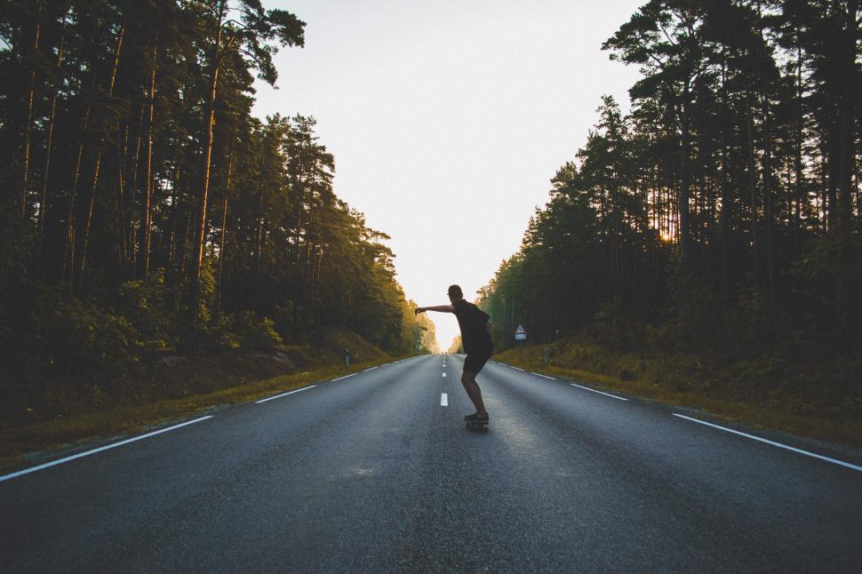 Free Image of Silhouette of person skateboarding on a deserted highway 