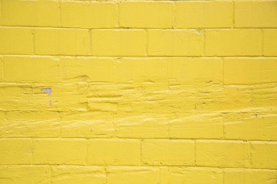 Free Image of Bright yellow painted brick wall in urban setting 