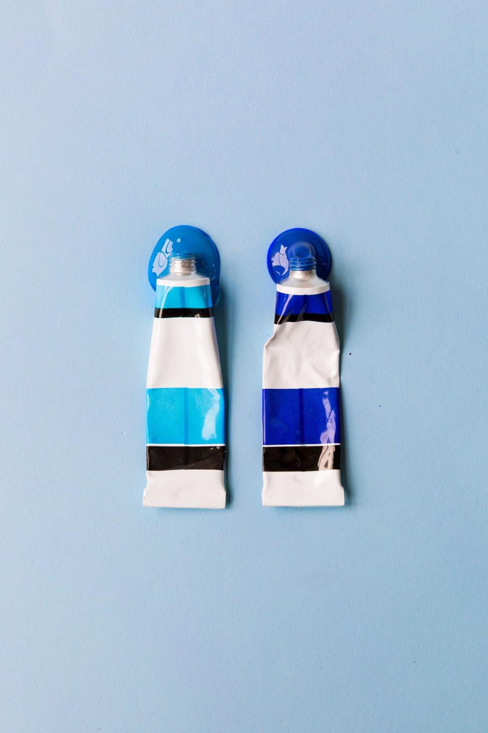 Free Image of Two tubes of blue and white paint on a light blue background 