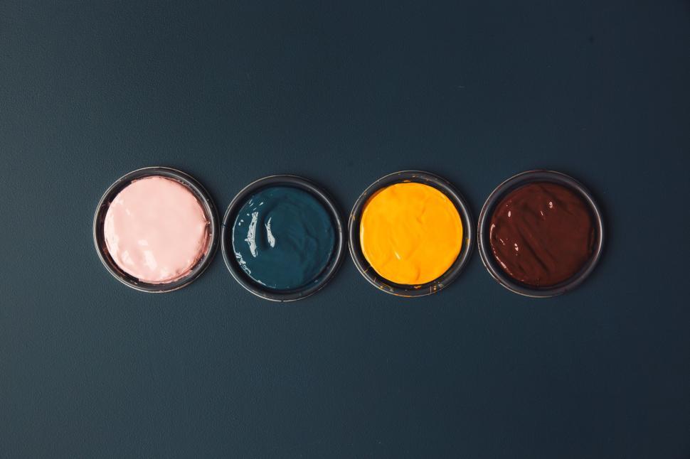 Free Image of Four cans of colorful paint on a dark blue surface 