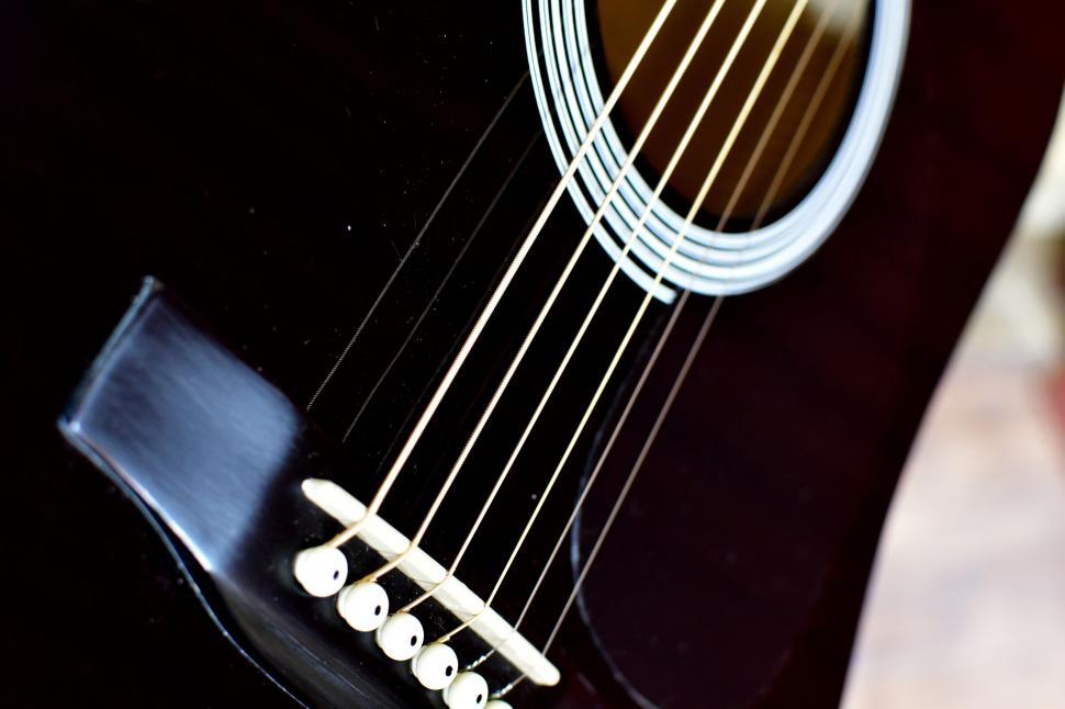 Free Image of Close up of black acoustic guitar strings and bridge 