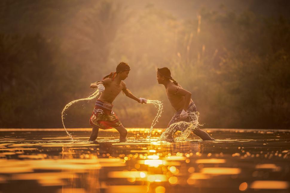 Free Image of Children play in water at sunset creating joyful splashes 