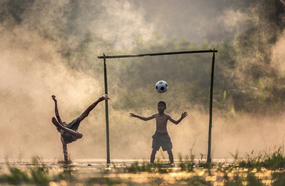 Free Image of Two children playing football in a misty field at dawn. 