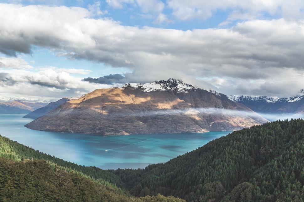 Free Image of Serene lake surrounded by mountains with cloudy sky 