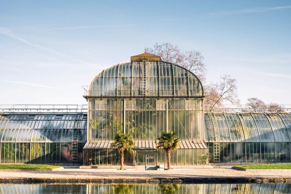 Free Image of Beautiful glass greenhouse with reflection in calm water 