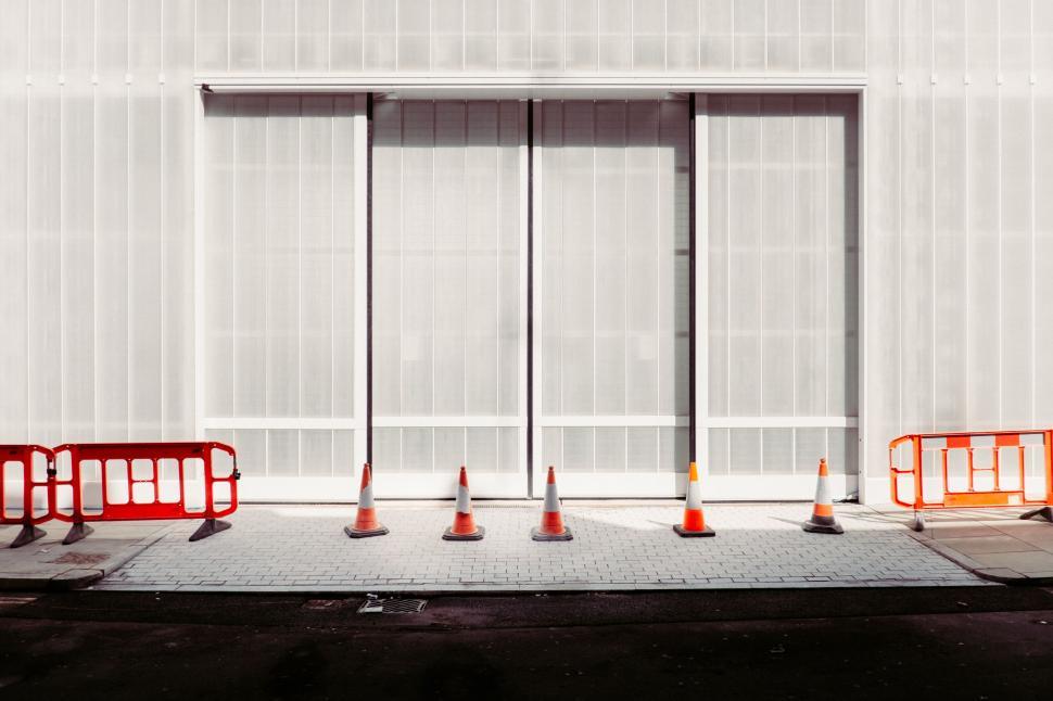Free Image of Construction zone barricades and cones outside modern building 