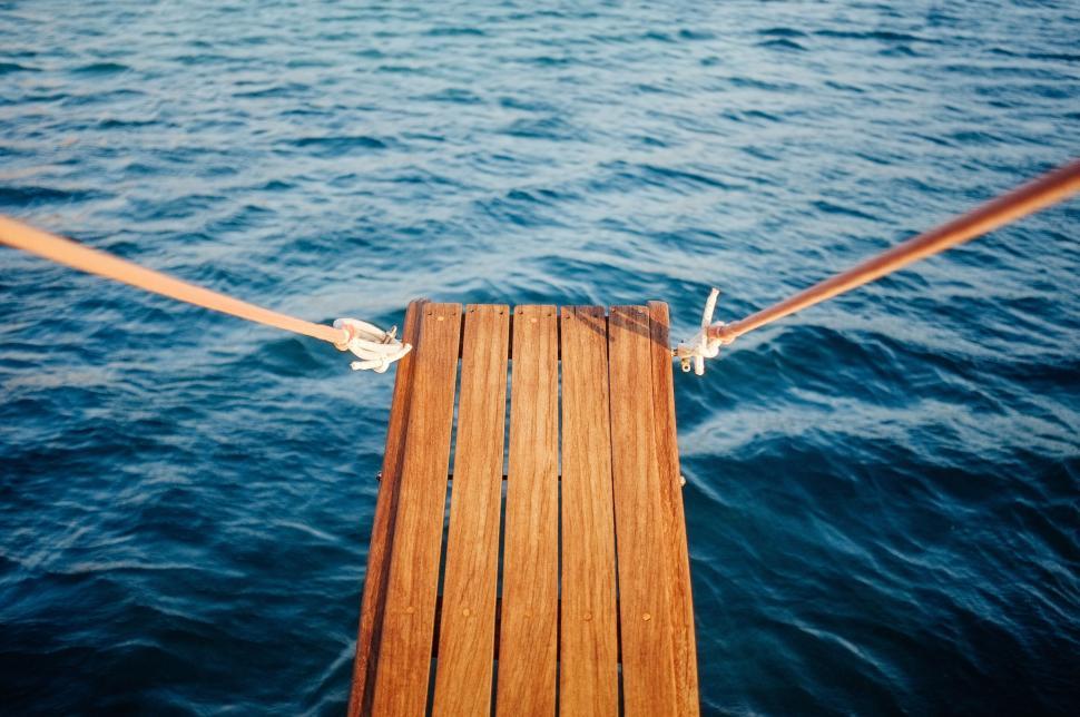 Free Image of Wooden dock extending into calm blue water body 
