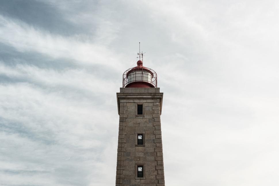 Free Image of Historic lighthouse standing tall against a cloudy sky. 