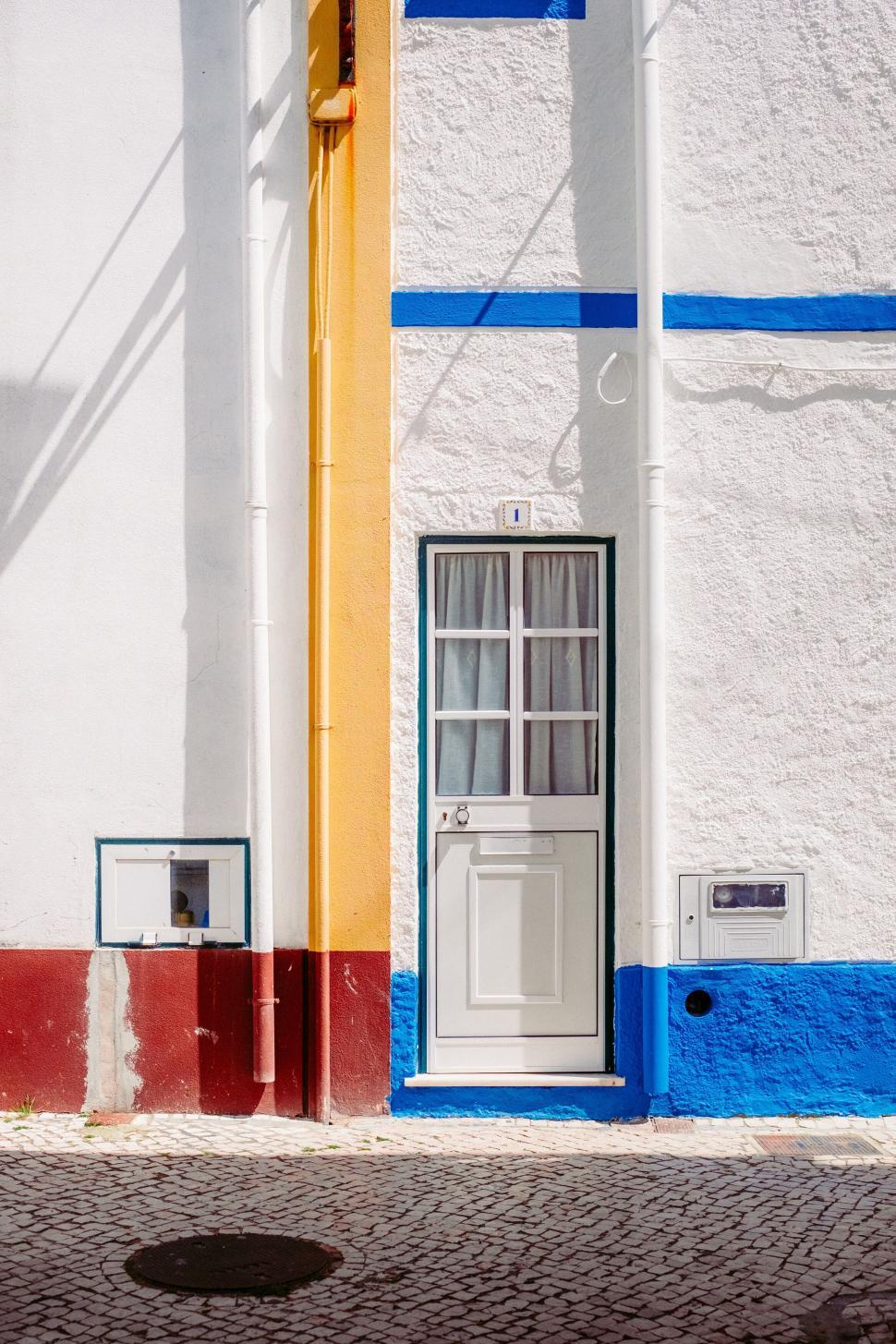 Free Image of Colorful house front with door and window on paved street 