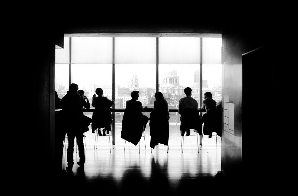 Free Image of Silhouettes of people sitting in a modern indoor space 