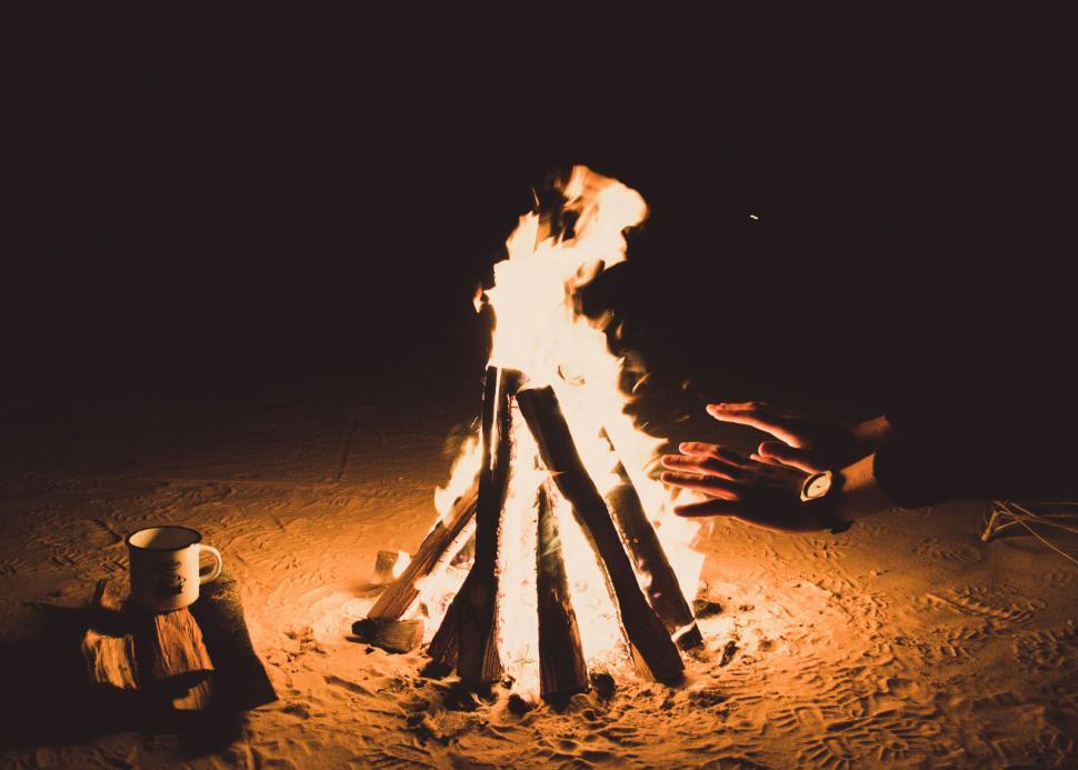 Free Image of Cozy campfire at night with hands warming by flame 