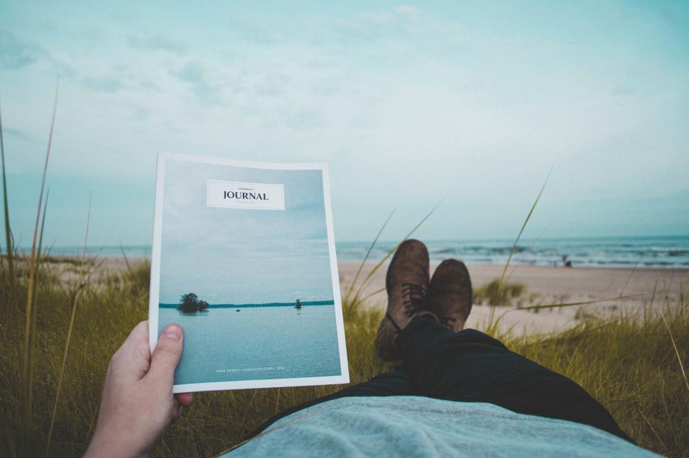 Free Image of Person reading journal while relaxing at beach 