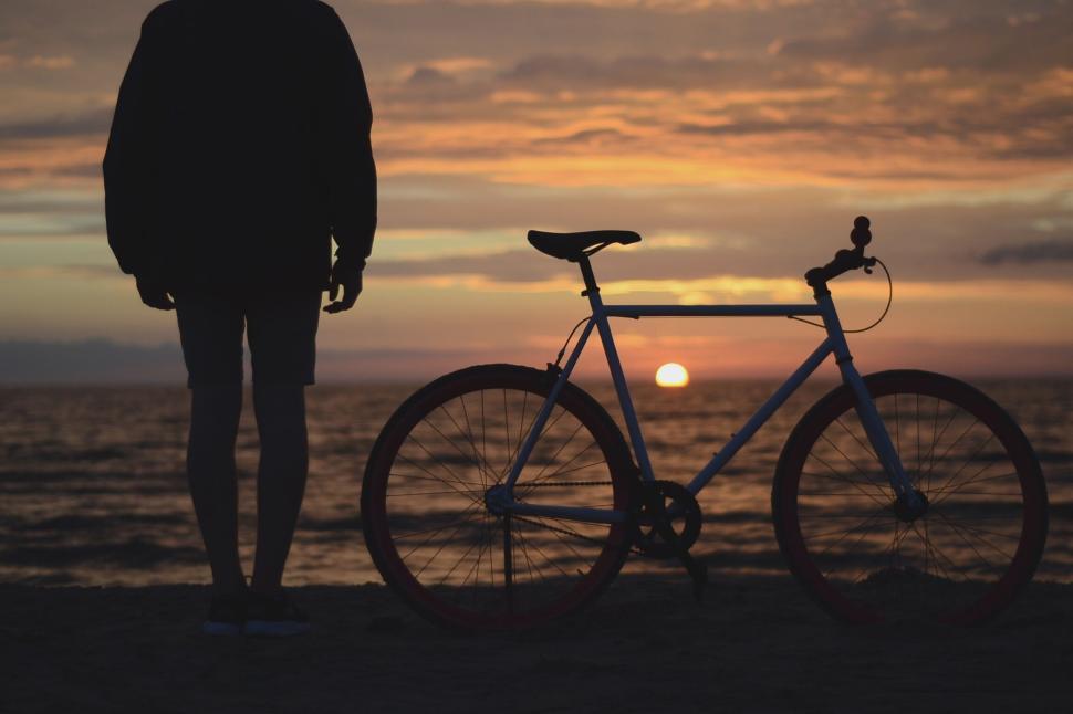 Free Image of Person and bicycle at sunset on the beach shore 