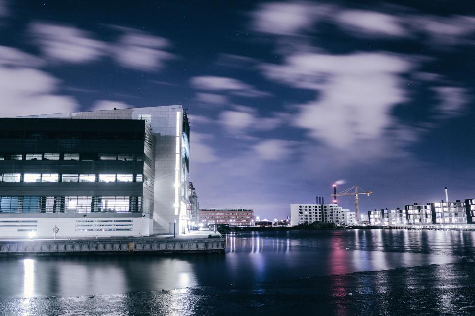 Free Image of Nighttime waterside with illuminated buildings and cranes 