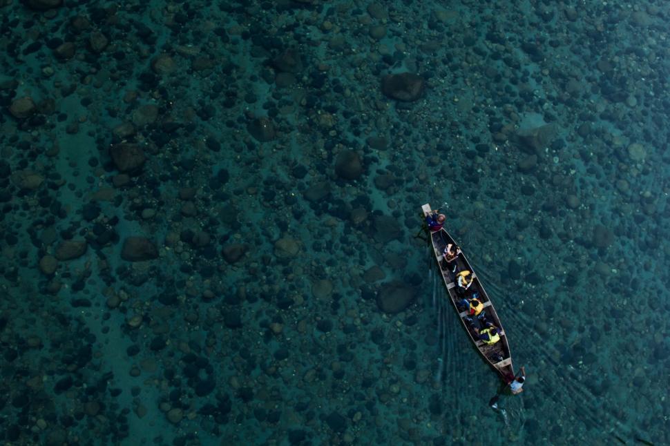 Free Image of Group in boat floats on the crystal-clear water surface 