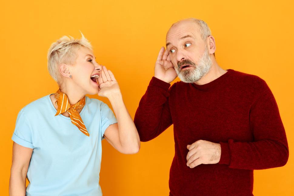 Free Image of Marriage, relationships, people and age concept. Attractive mature woman with short gray hair screaming while addressing to her husband who is holding hand at his ear because of hearing problem 