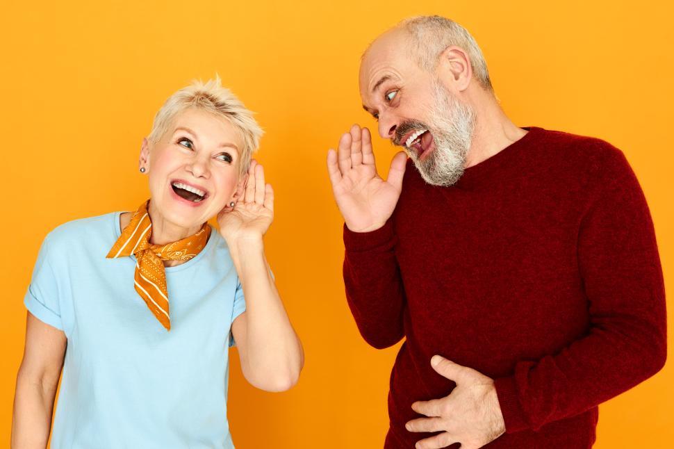 Free Image of Body language. Portrait of two funny elderly Caucasian pensioners with hearing problem having conversation, keeping hands at ear and shouting but can not make out any words. Deafness concept 