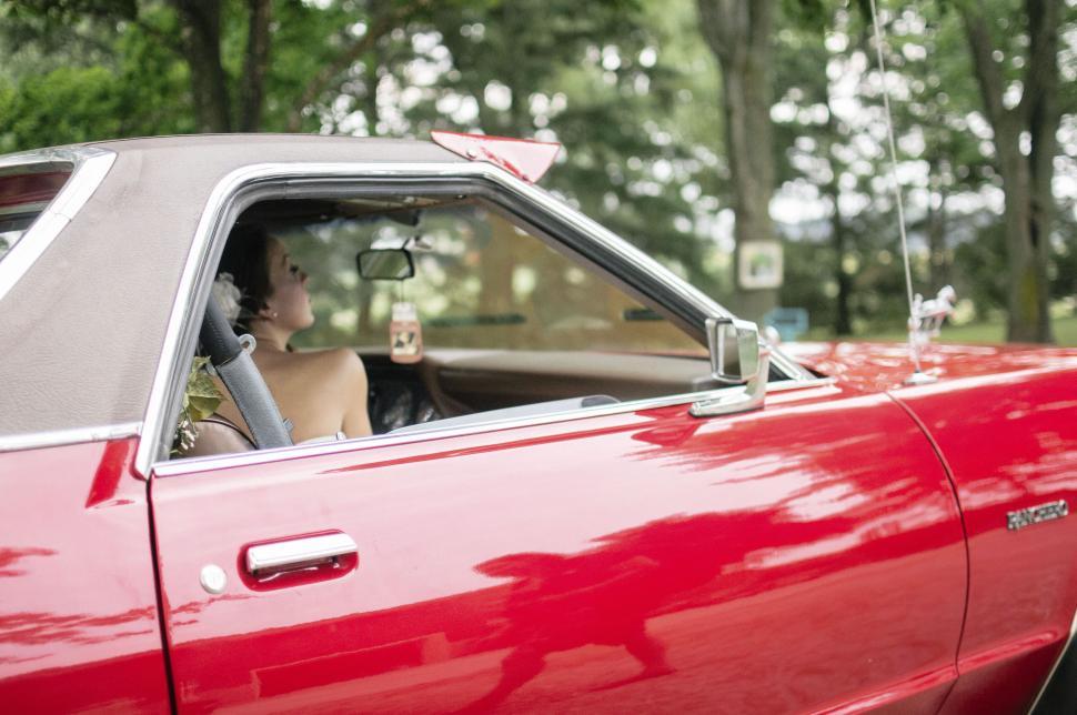 Free Image of Person driving a vintage red convertible car outdoors 