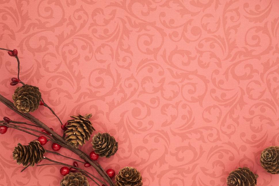 Free Image of Festive pinecones and red berries with pinkish pattern 