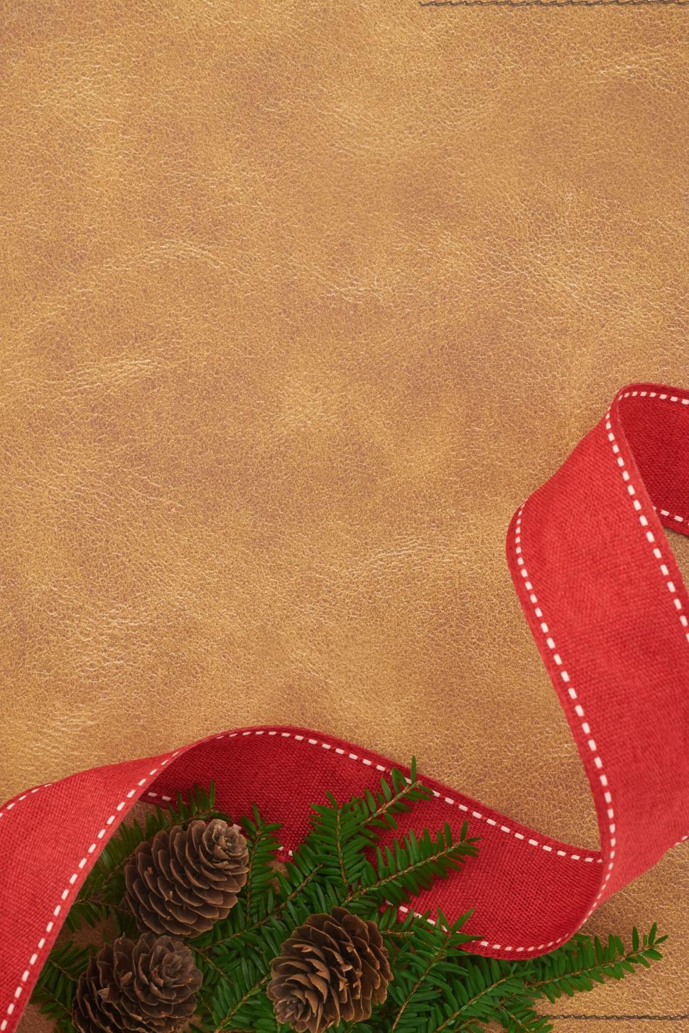 Free Image of Brown leather background with festive pinecones and ribbon 
