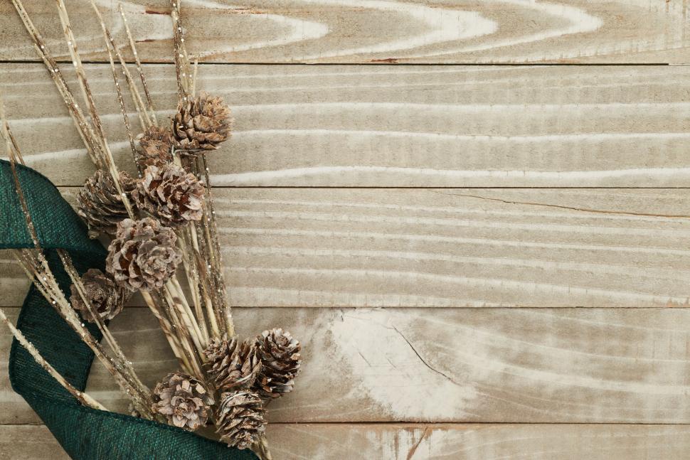 Free Image of Dried cones and twigs with green ribbon on wooden board. 