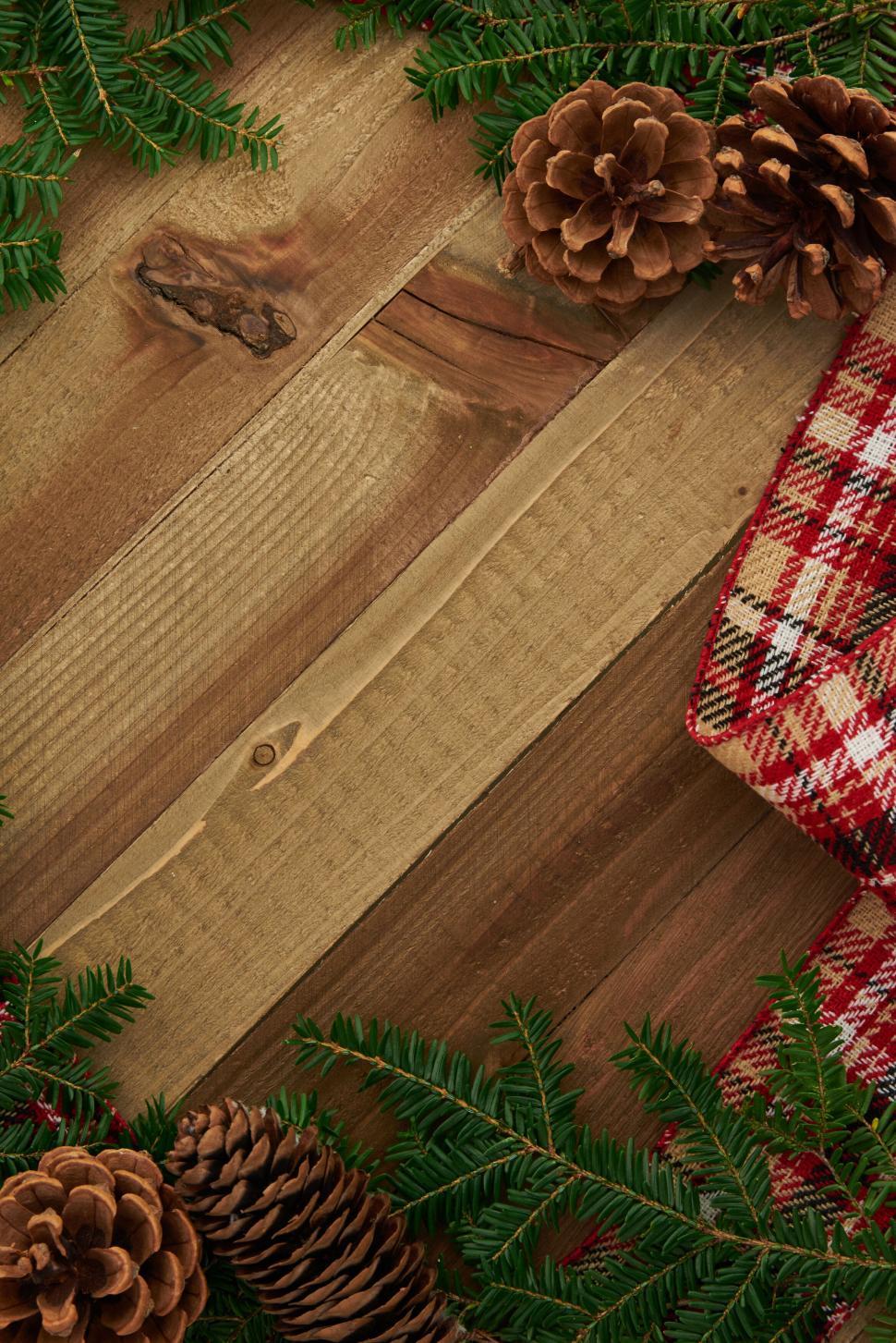 Free Image of Festive pinecones and plaid cloth on rustic wood boards 