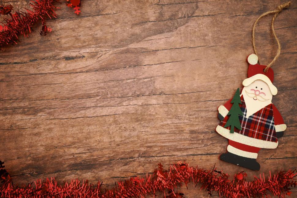 Free Image of Wooden table with Santa Claus ornament and red tinsel 