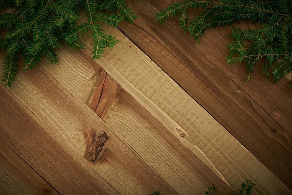 Free Image of Wooden plank background with pine branches on edges. 