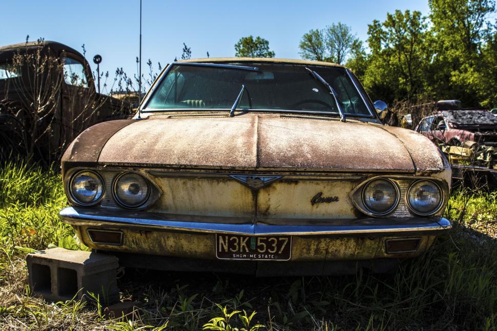 Free Image of Old rusty car parked in a field on a sunny day. 