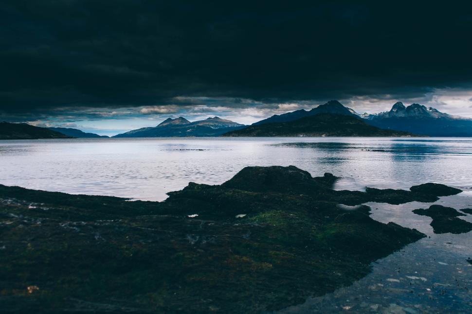 Free Image of Dark stormy sky over a serene mountain lake scene. 