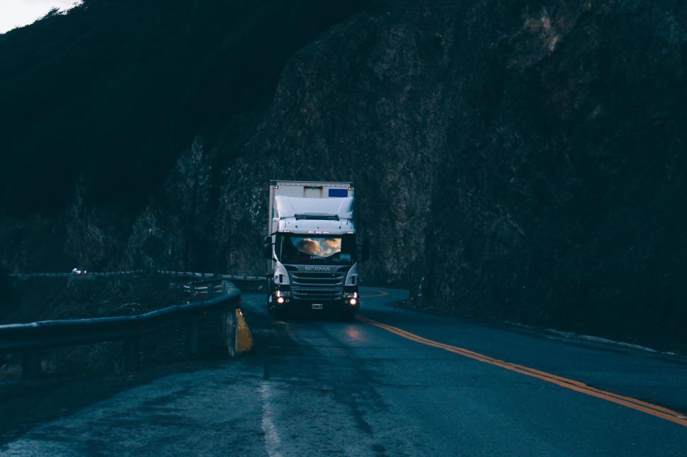 Free Image of Truck driving on winding mountain road in twilight. 