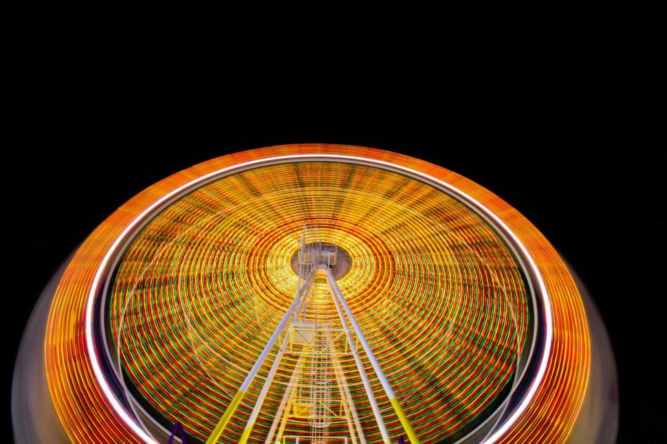 Free Image of Ferris wheel spinning at night creating a light pattern. 